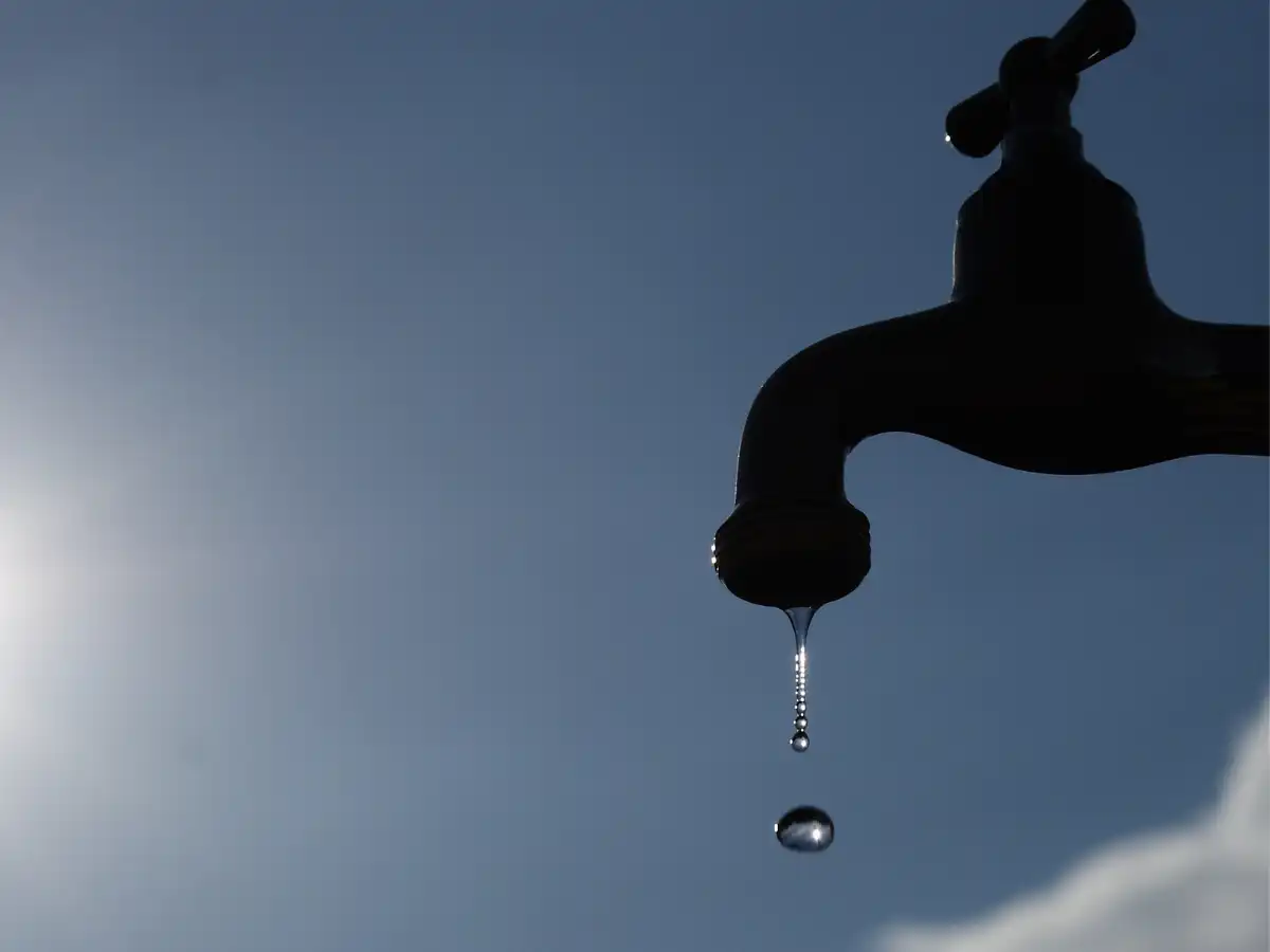 青空の背景。蛇口から水が滴っている画像